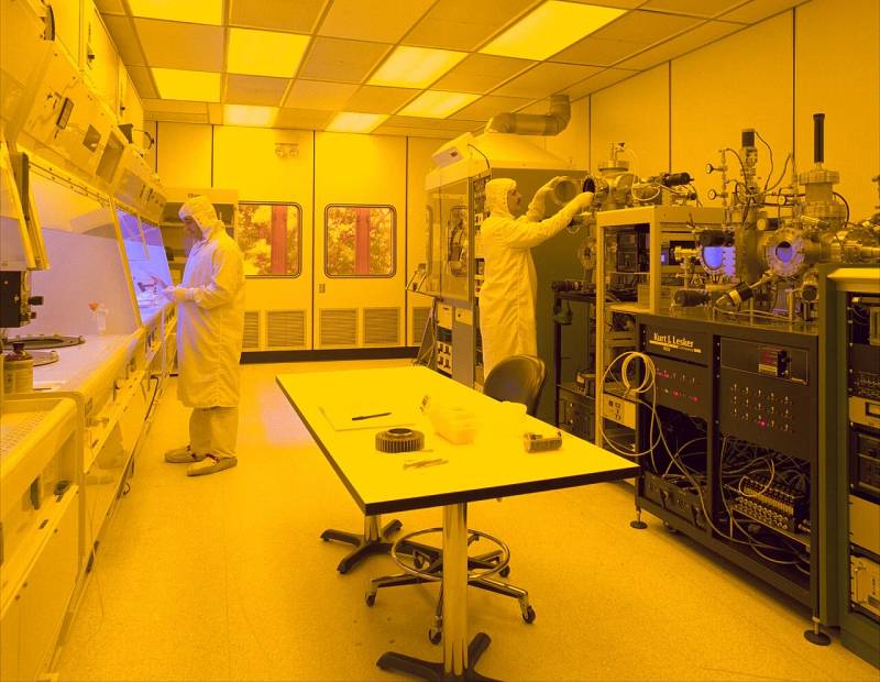 Ultra-clean semiconductor fabrication environment with automated material handling systems and yellow photolithography lighting for advanced wafer processing.