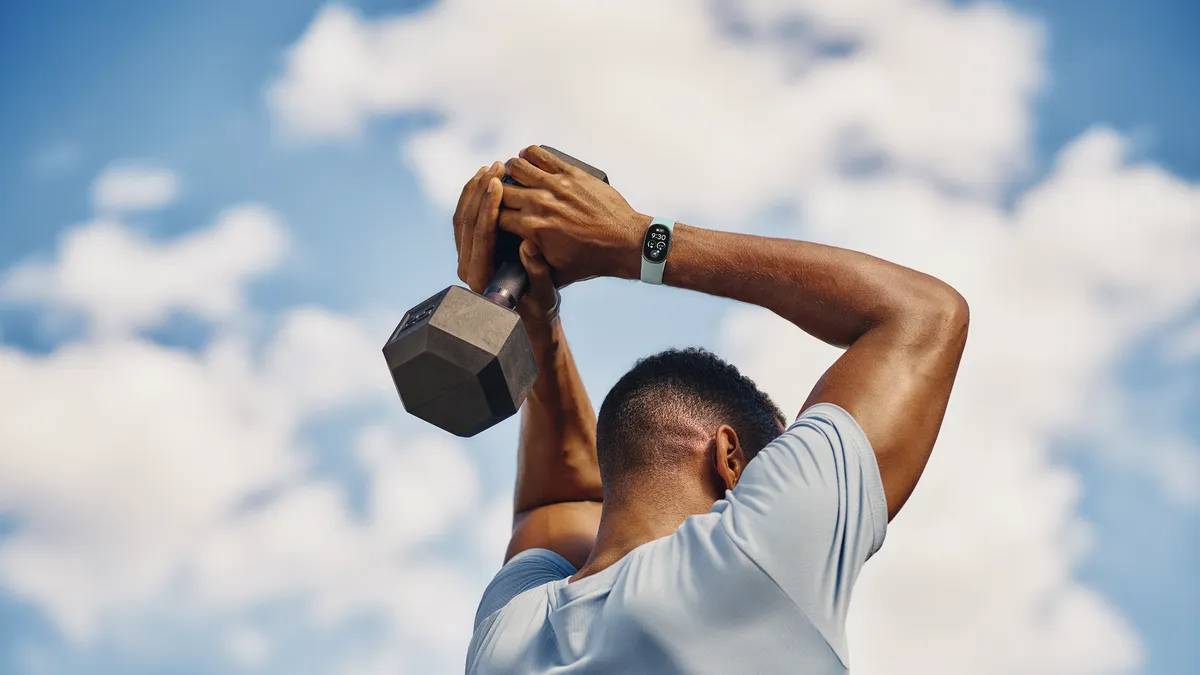 Google Fitbit Edge fitness tracker with hybrid OLED display and Active Sport Band shown on wrist during an outdoor workout.